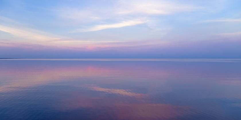 pastel blue and pink sky reflected in a calm ocean