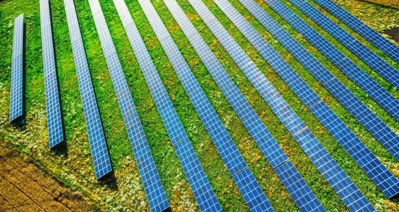 Aerial view of blue solar panels on green field, Poland
